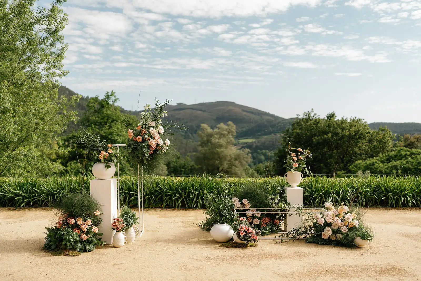 Wedding ceremony altar with organic pinkish flowers, columns and vases. Surrounded by the beautiful landscapes of the Minho region, Portugal.