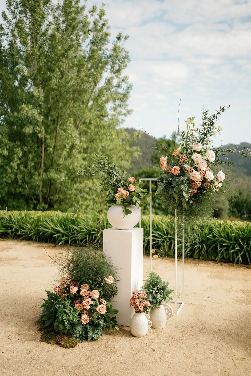 Close-up of the ceremony altar decoration, composed by organic flowers in pink shades, vases and columns.