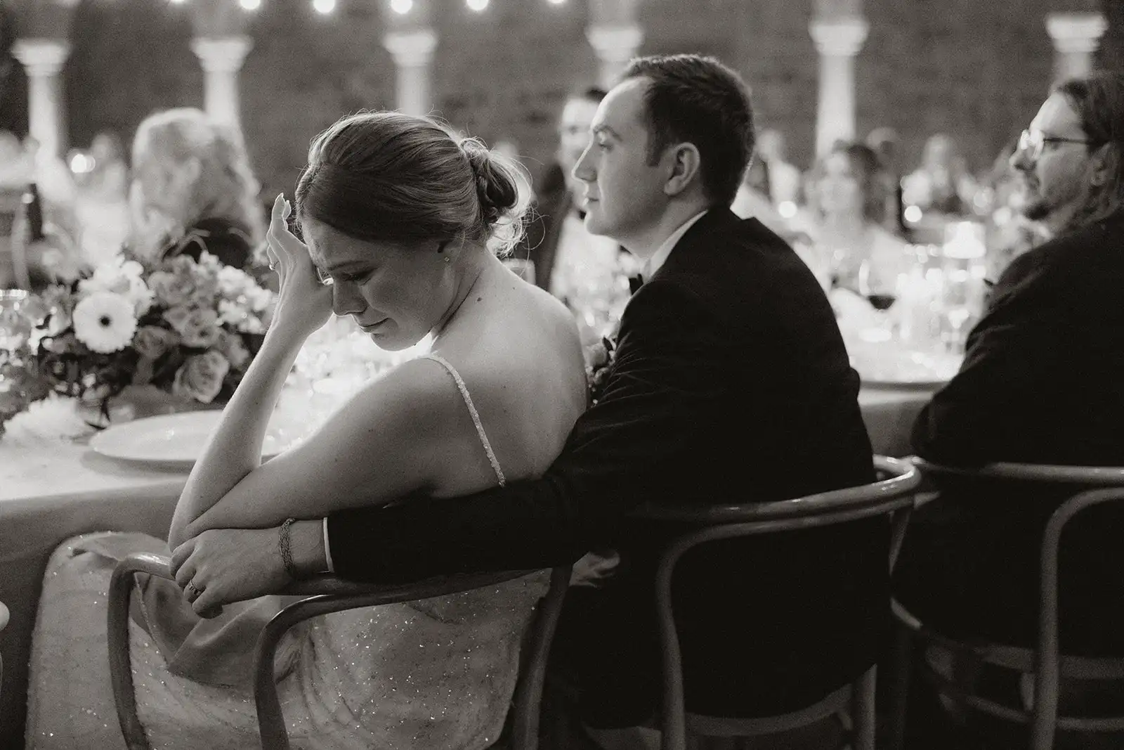 Candid black and white moment of the emotional bride and groom during the speeches at the dinner wedding.