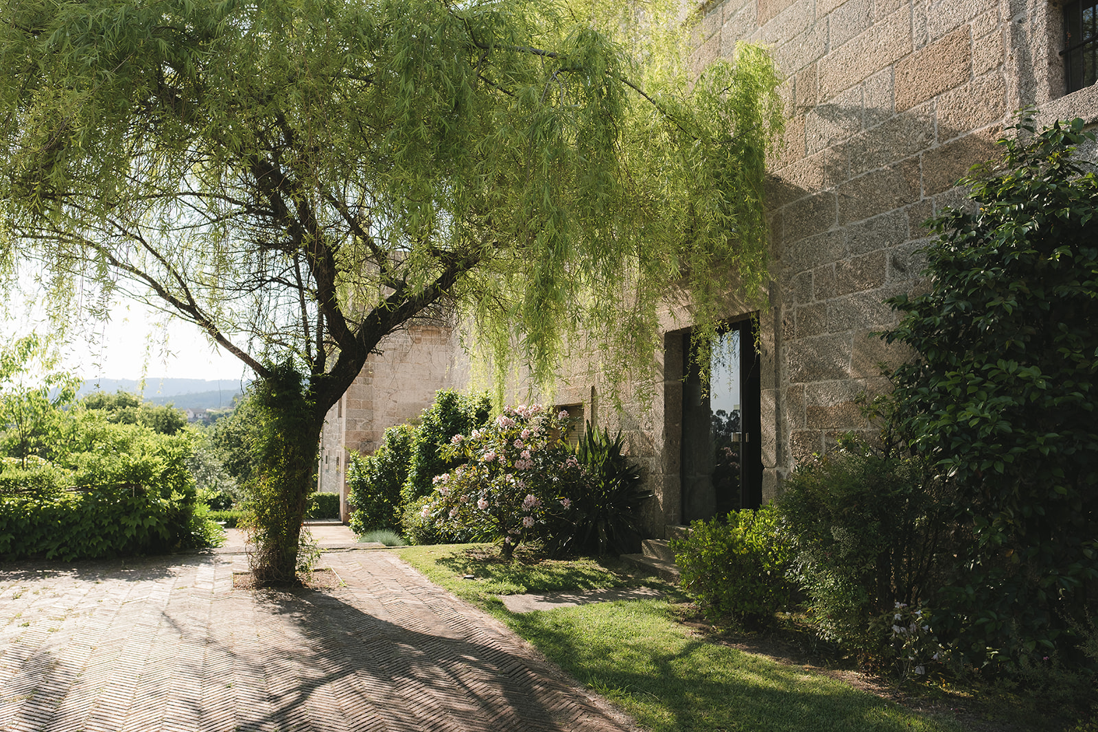 Beautiful corner at the entrance of the terrace of Pousada de Amares, with the trees and bushes and the old centuries stone facade.