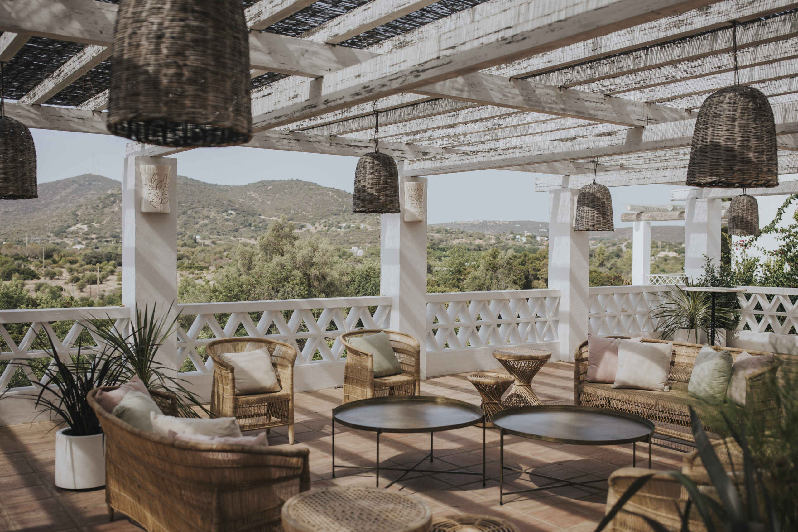Vila Monte Algarve terrace with wooden cocktail wedding furniture with beautiful view to the Algarve mountains landscapes. Typical Mediterranean architecture wedding venue in Portugal.