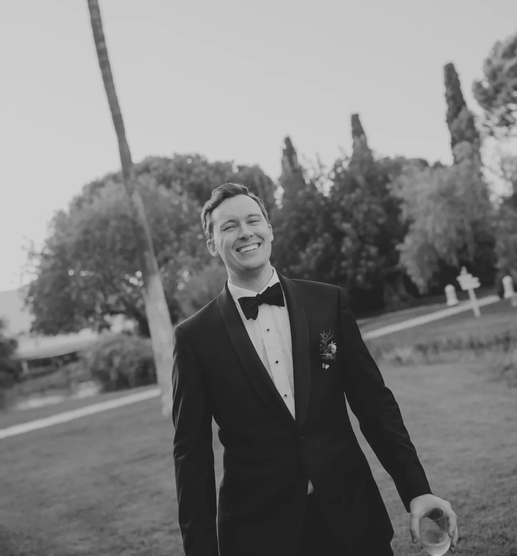 The groom smiling in his wedding suit. A relaxed pose while walking. Black and white photo.