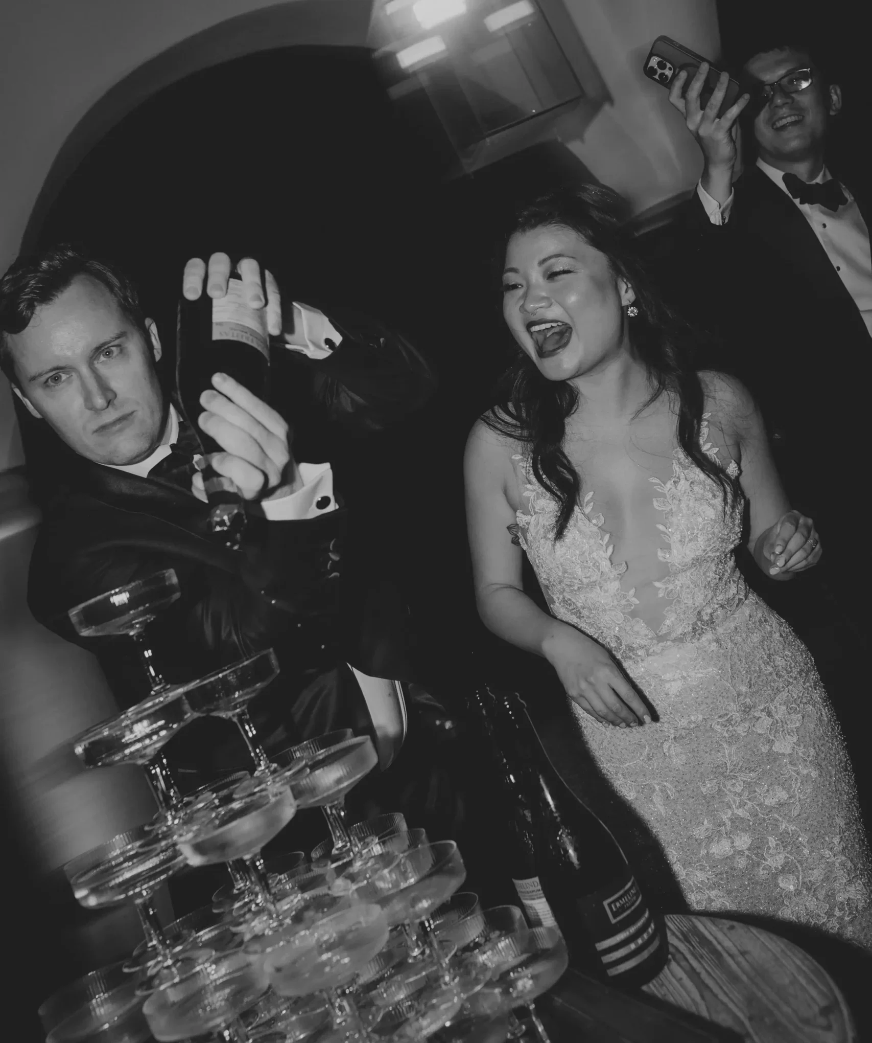 Candid fun moment during the champagne tower toast with bride and groom. Black and white edition. Portugal intimate wedding.