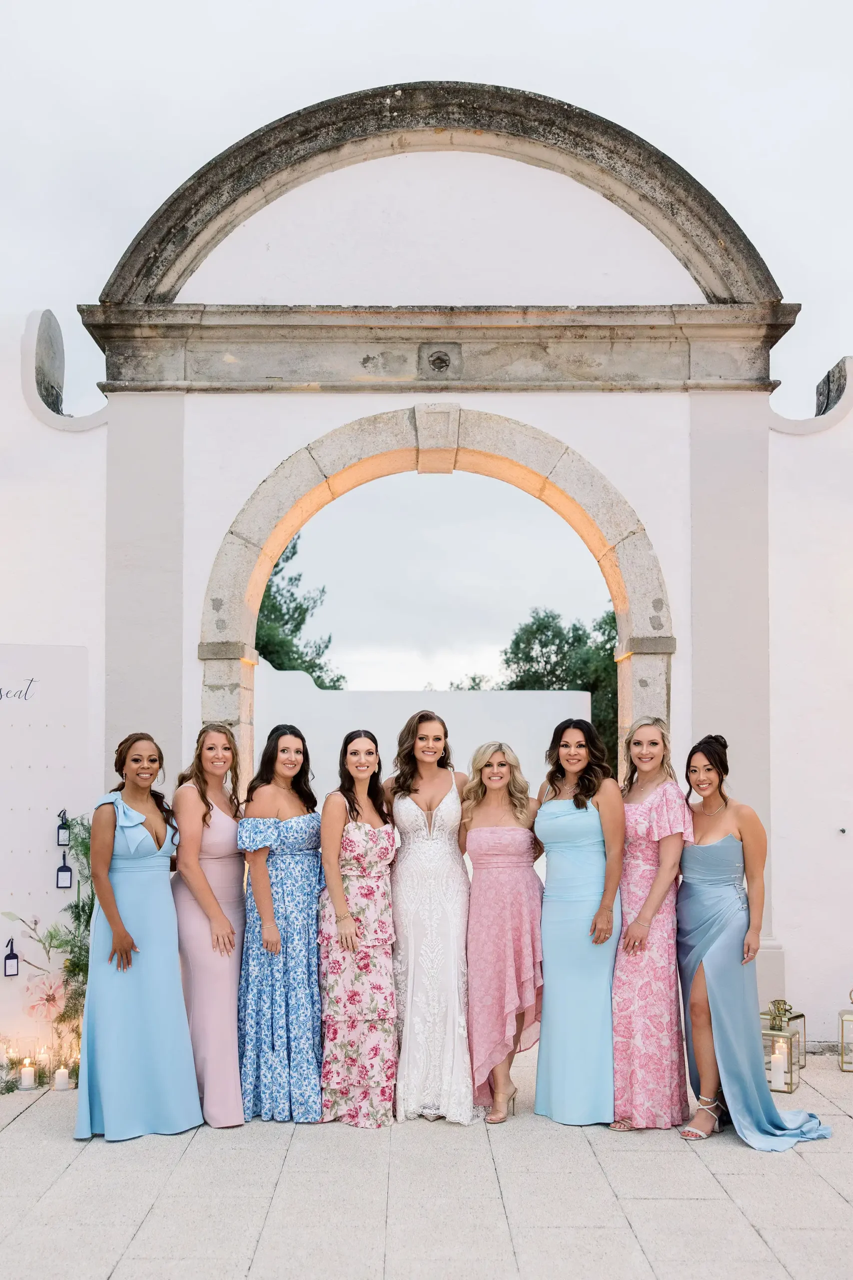 Bridal party photoshoot with bride. Light blue and pink blush scheme color and floral patterns bridesmaids dresses.