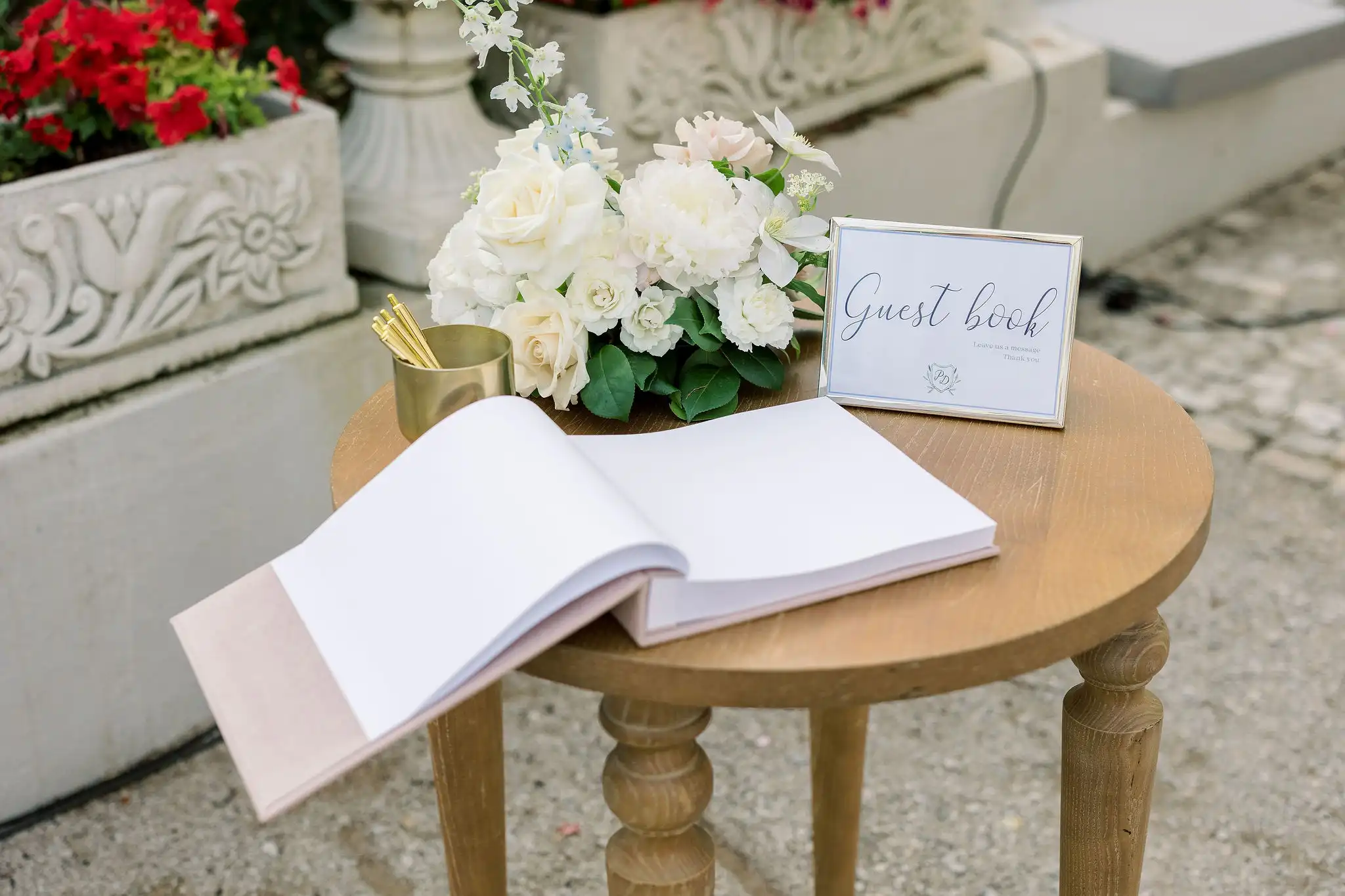 Guest book wedding table decor with a white and pink flower arrangement, guestbook sign and pens.