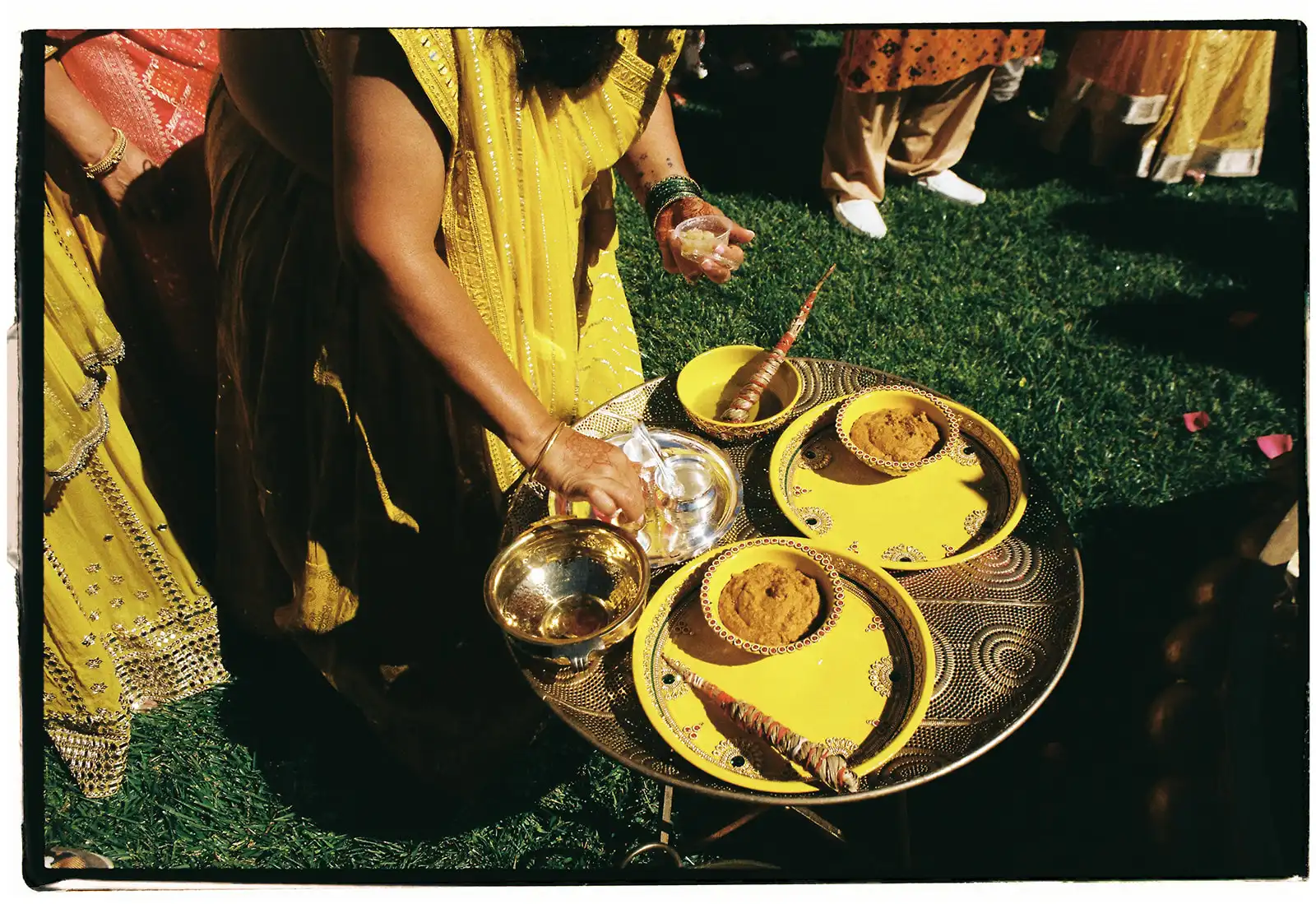 Indian wedding in Portugal. Haldi ceremony moment with preparations of the turmeric paste. Yellow and gold decoration.