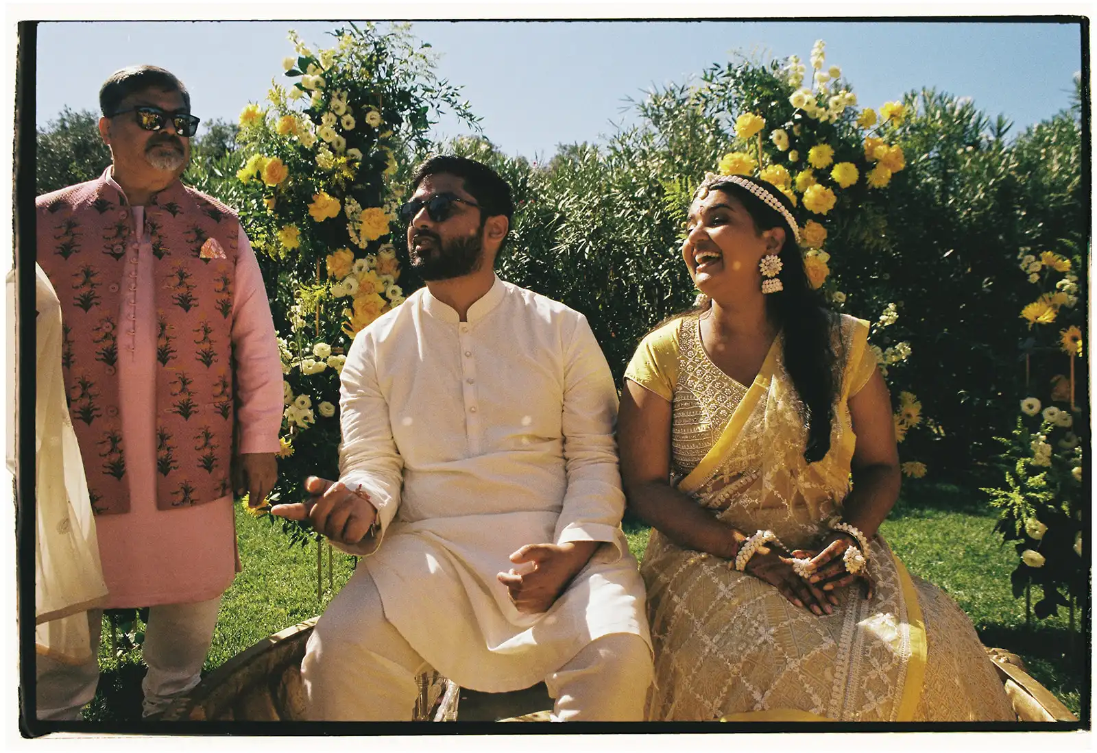 Indian wedding in Portugal. Haldi ceremony with decor in yellow and gold. Bride and groom smiling inside the badjot in Indian yellow outfits.