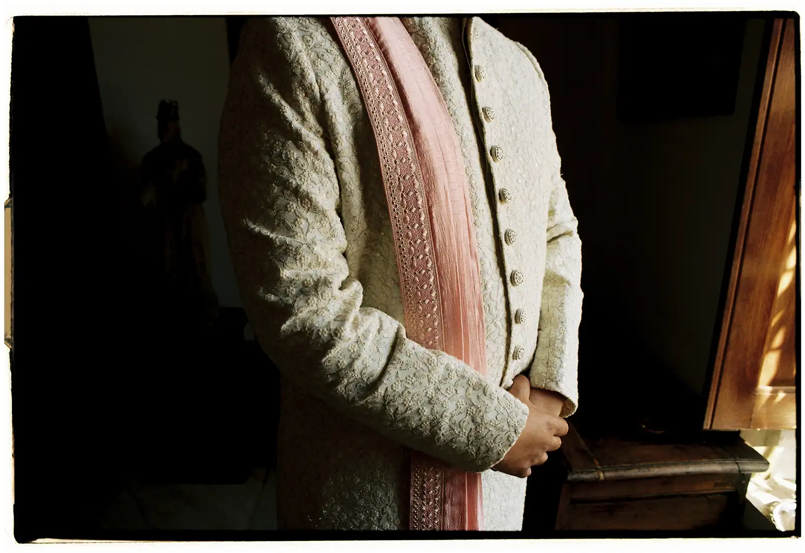 Close-up of a Indian groom with blush pink, beige and gold detailed outfit.