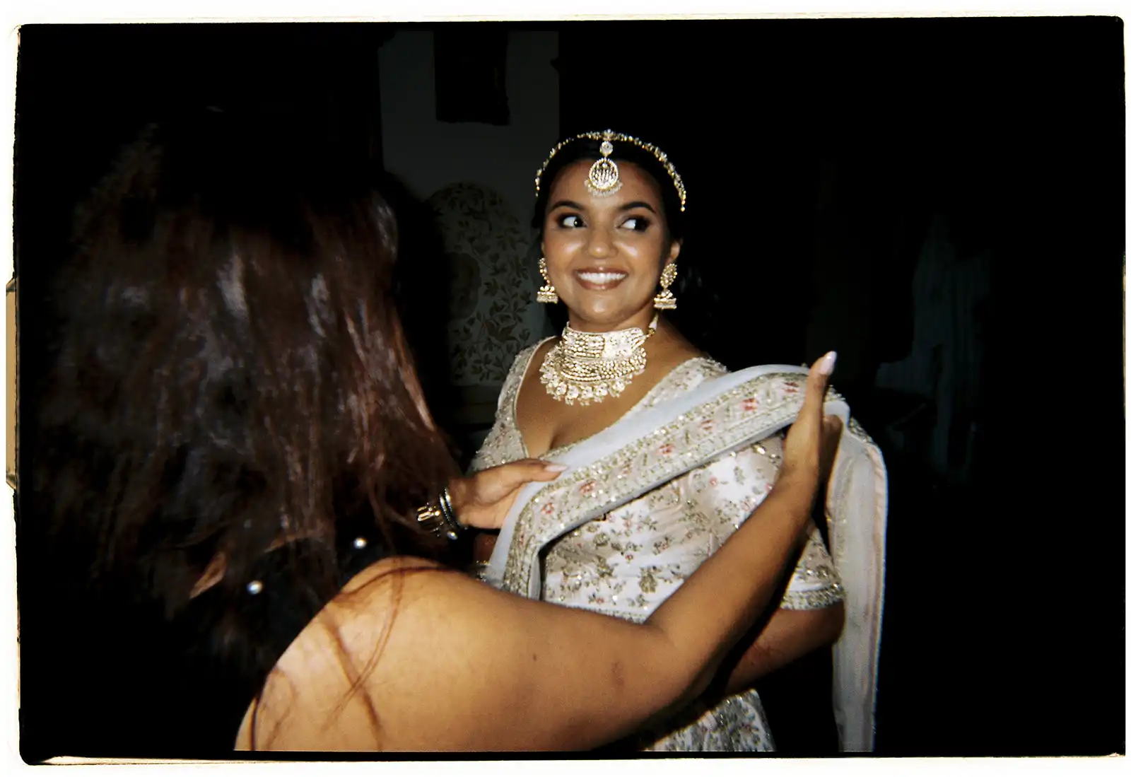 Happy Indian bride finalizing preparations for her Indian wedding ceremony in Portugal. Details and accessories of the Indian outfit.