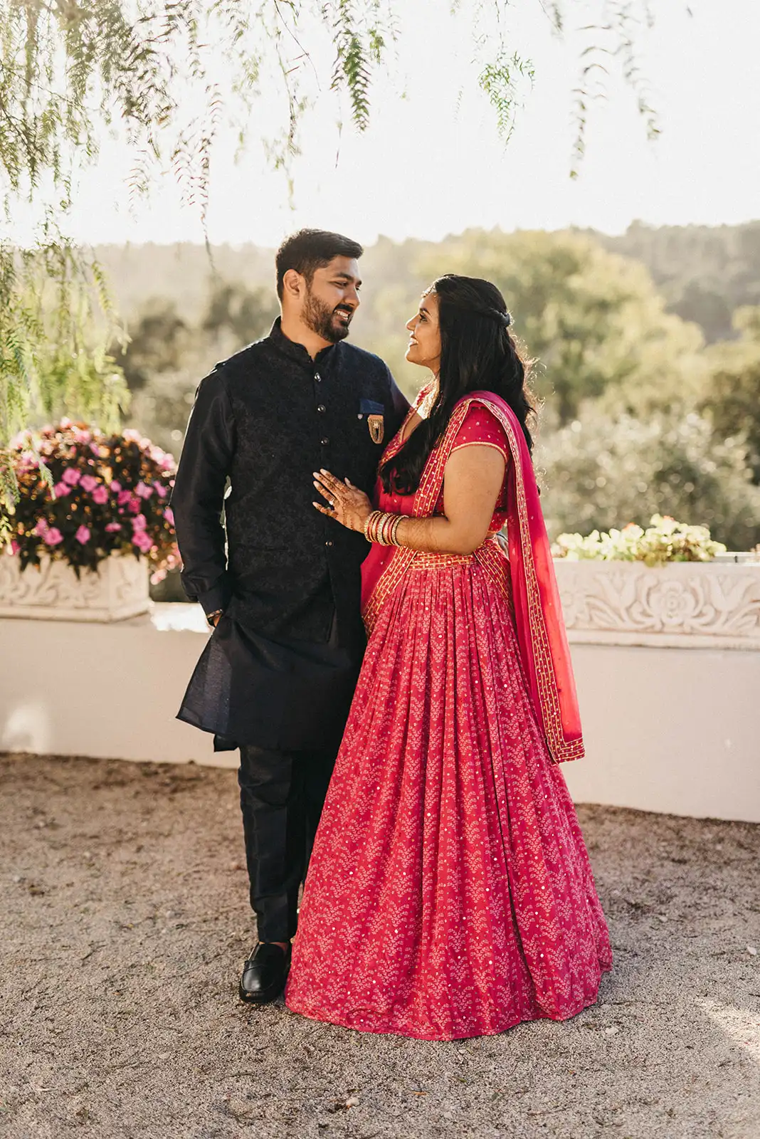 Indian bride and groom ready for the sangeet night in a Portuguese landscape. Groom in black outfit and bride in a pink dress with gold details.