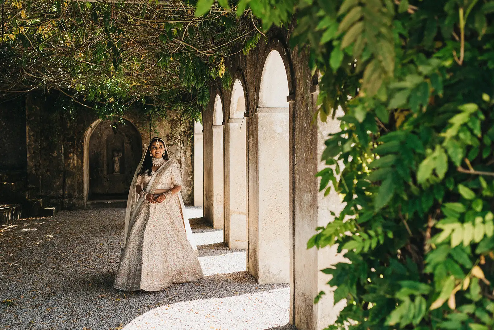 Indian bride in a beige and gold dress. Enchanted garden-style venue in Portugal.