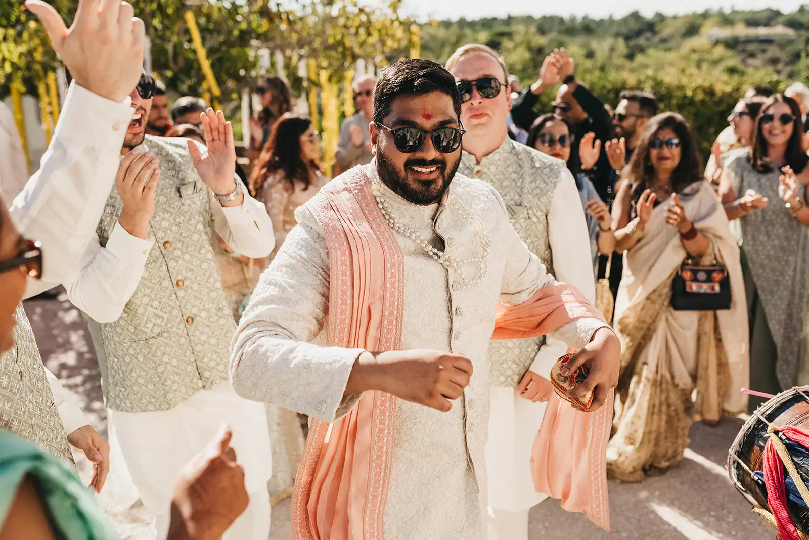 Indian Baarat in Portugal. Groom enjoying and dancing, in his neutral outfit, with his family and friends.