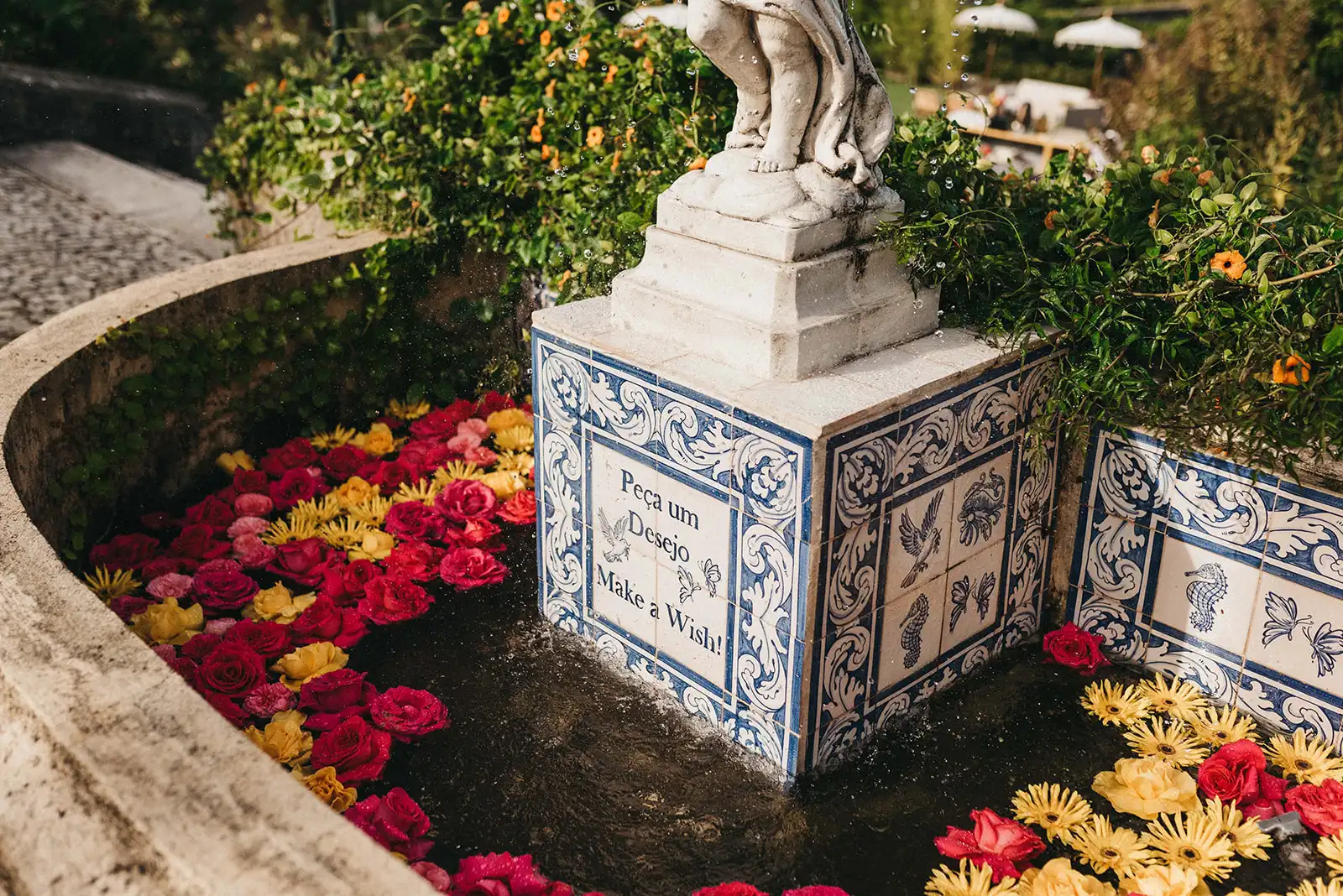 Indian wedding in Portugal details. Venue fountain with portuguese tiles with yellow and pink flowers floating in the water as decoration.